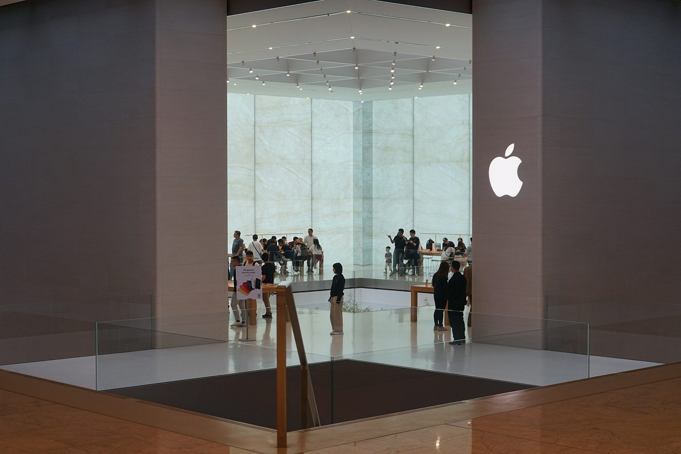 The glass storefront of an Apple Store in China, its logo lit above the entrance