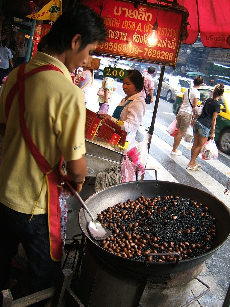 A street vendor roasts chestnuts in a large wok of hot sand and sugar, the traditional method behind China's popular autumn snack.