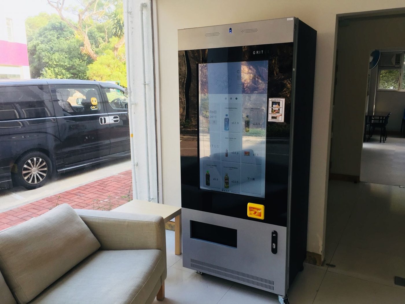A vending machine stocked with drinks and snacks stands in a hallway of a university student residence building.