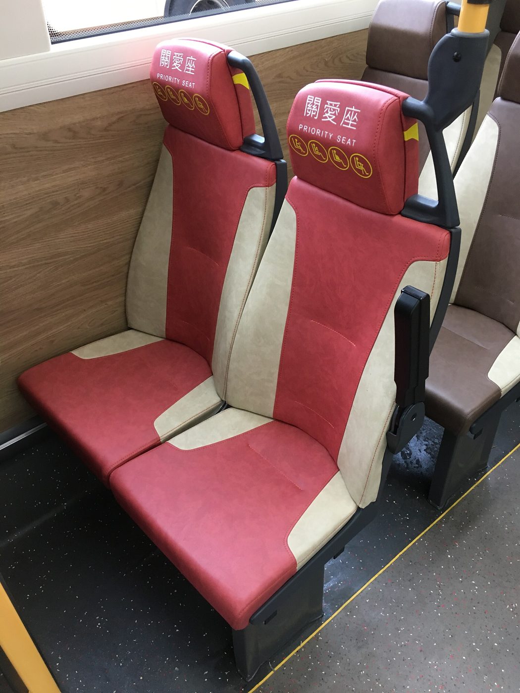 Blue priority seats near the front of a city bus, marked with signage for elderly, pregnant, and disabled passengers.