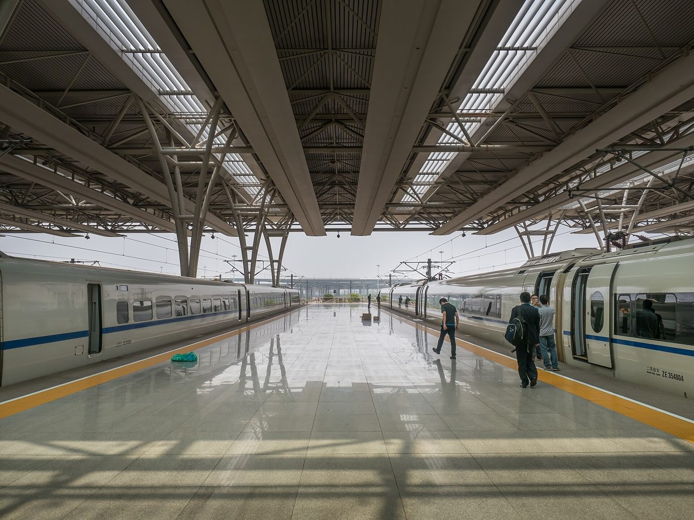 A high-speed train waiting at the platform of Shanghai Hongqiao Railway Station, with passengers on the platform.