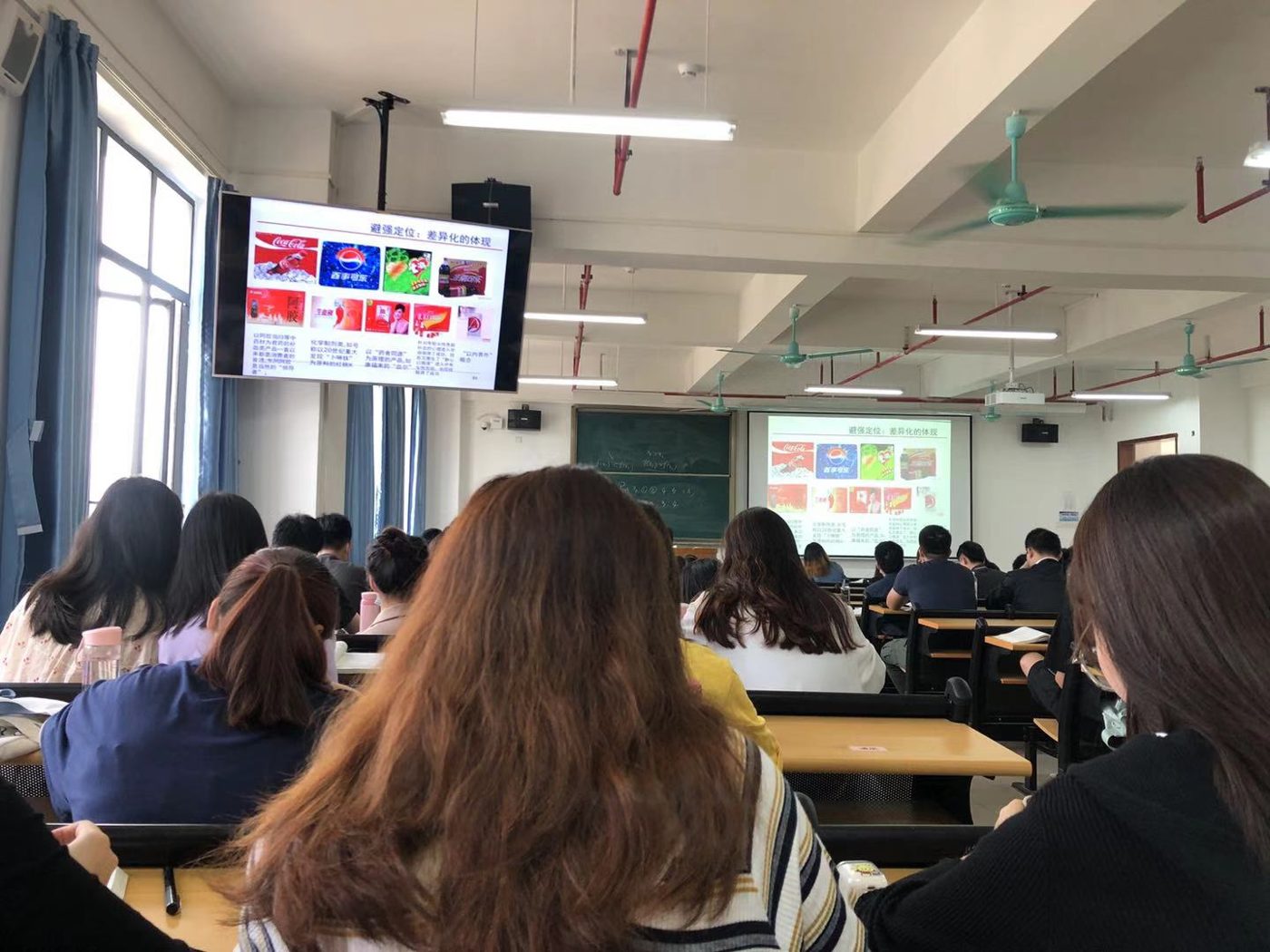 Students in a Chinese university lecture hall watching a lesson on a projector screen
