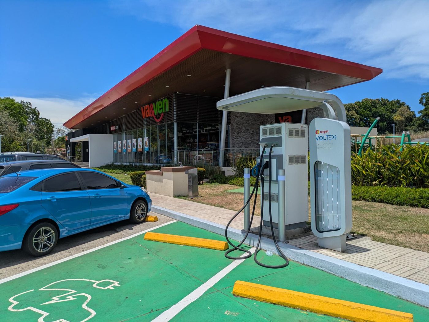 An electric car charging at a station beside a highway service stop