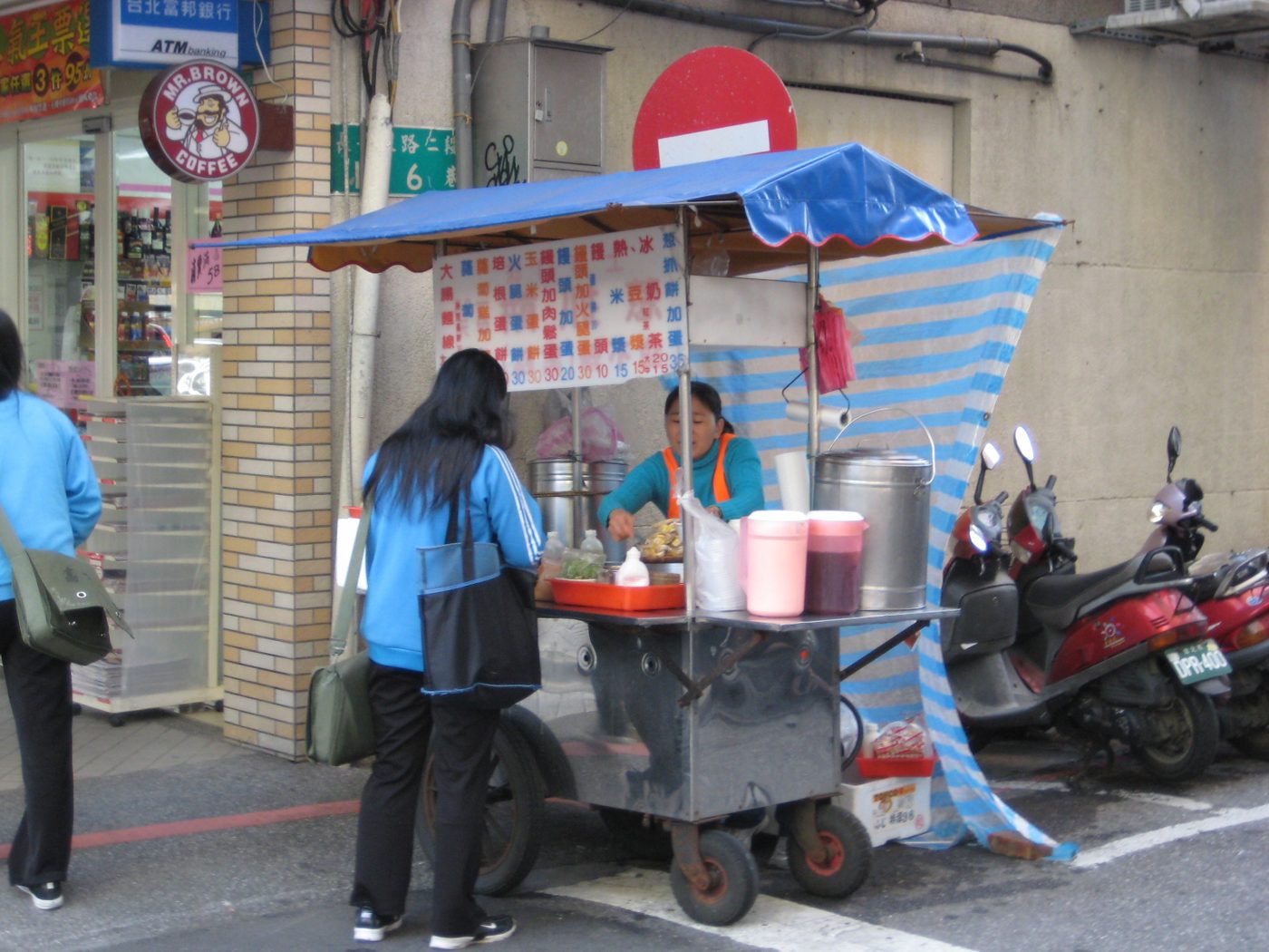 A street vendor in Taipei frying turnip cakes and other breakfast food at her cart-side stall.