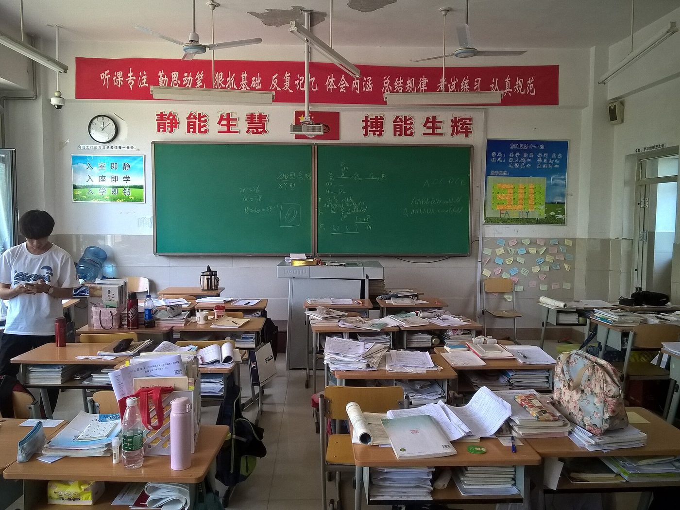 Students sit at desks in a Chinese classroom, with student-made banners hanging on the wall behind them