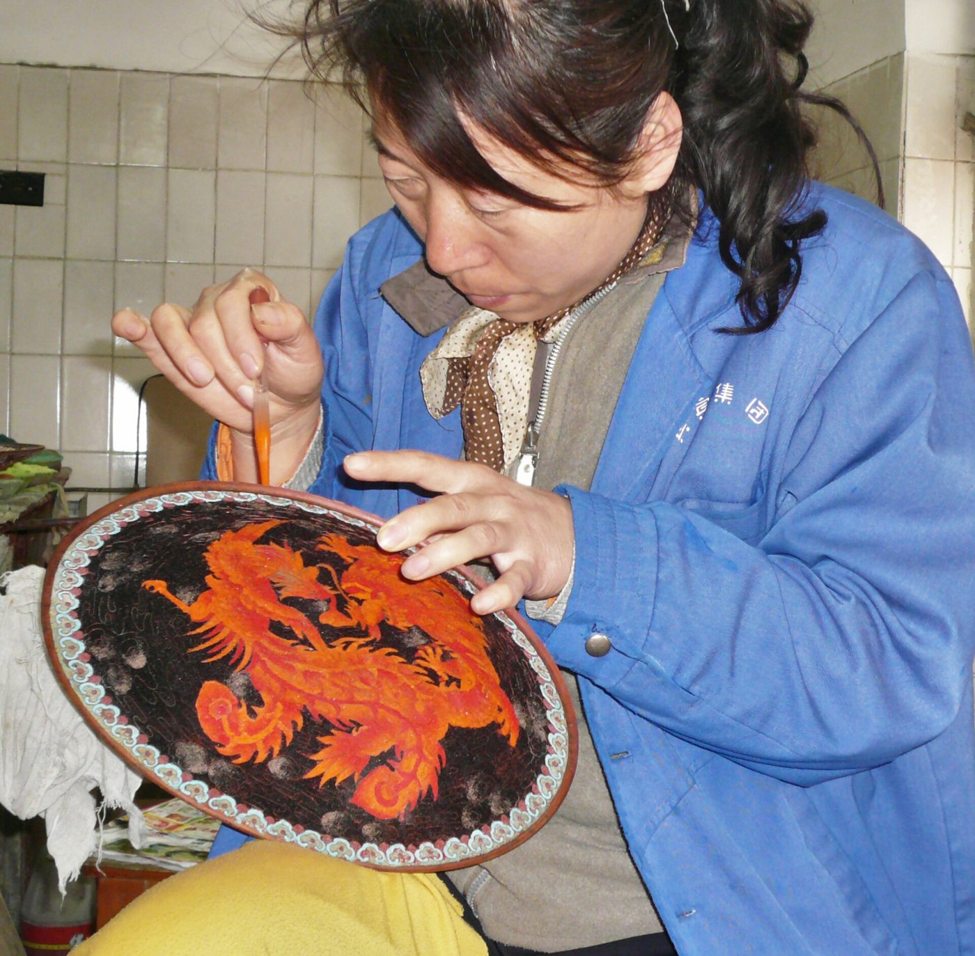 Close-up of artisans applying colored enamel to metal cloisonne vases in Beijing