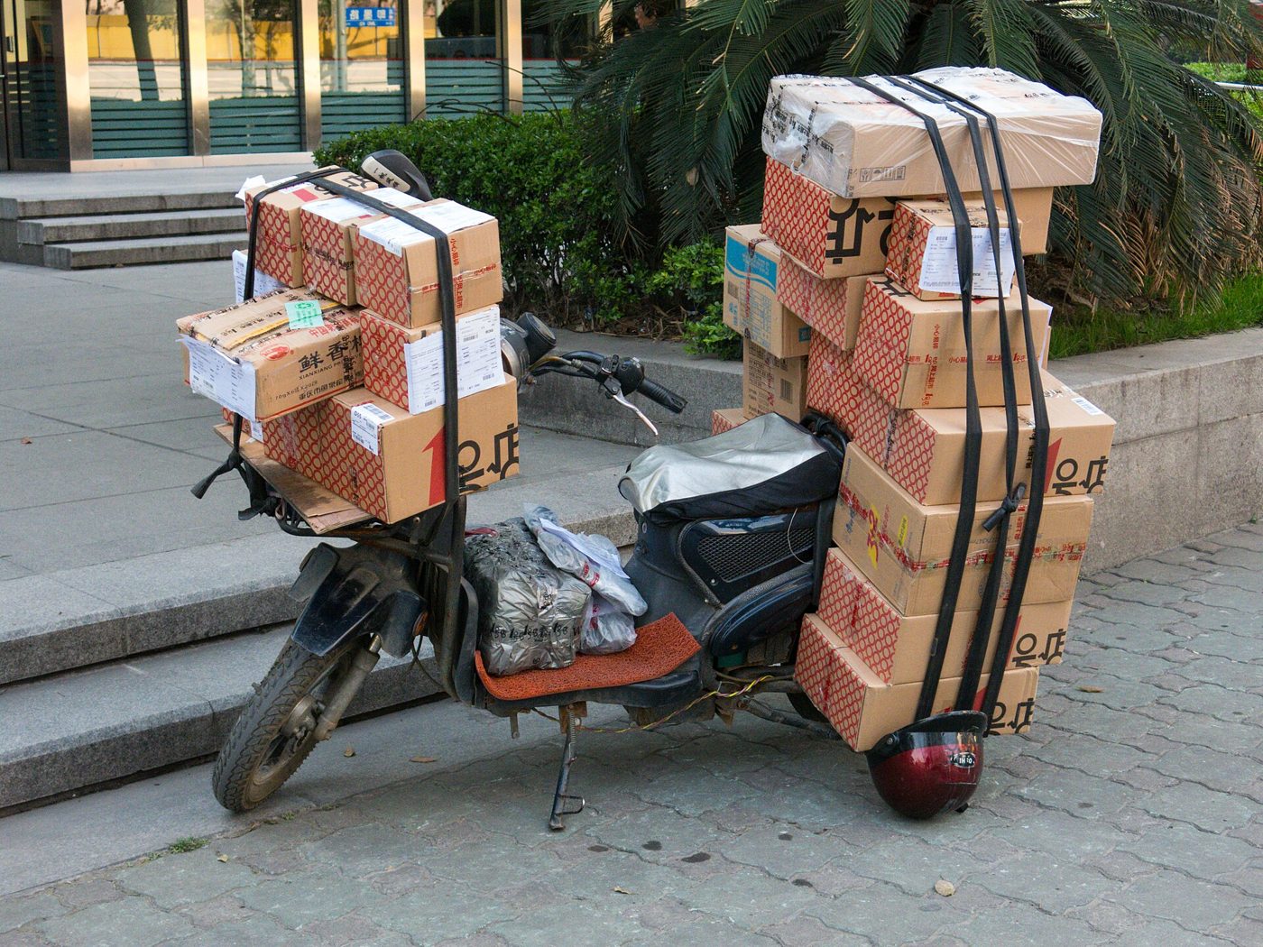 A delivery van stacked with cardboard packages on a city street in China