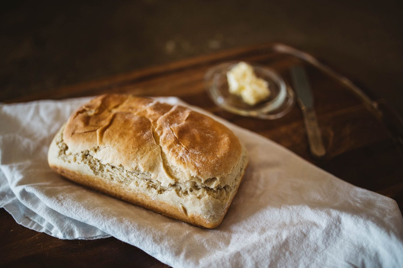 A fresh loaf of bread with butter on a wooden board