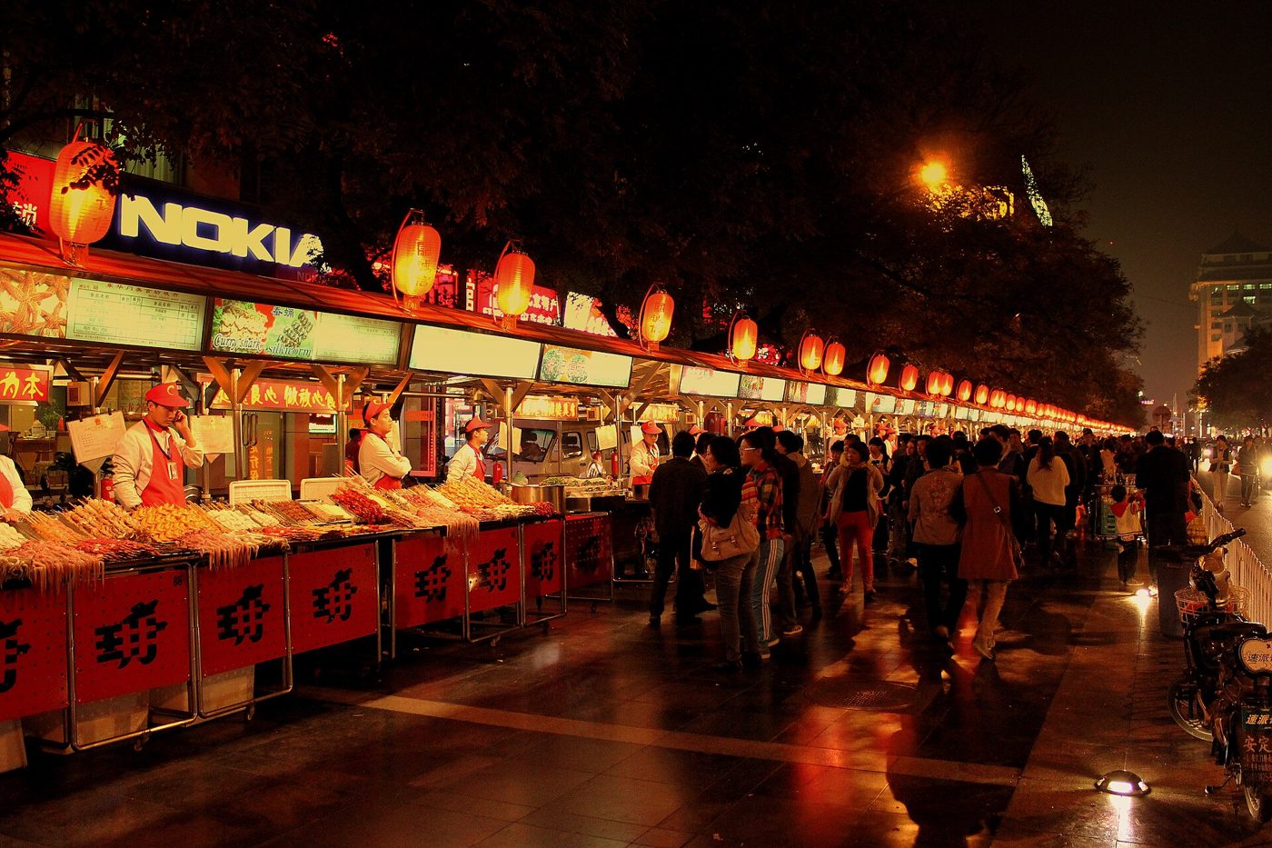 Lit food stalls lining a night market street in Beijing