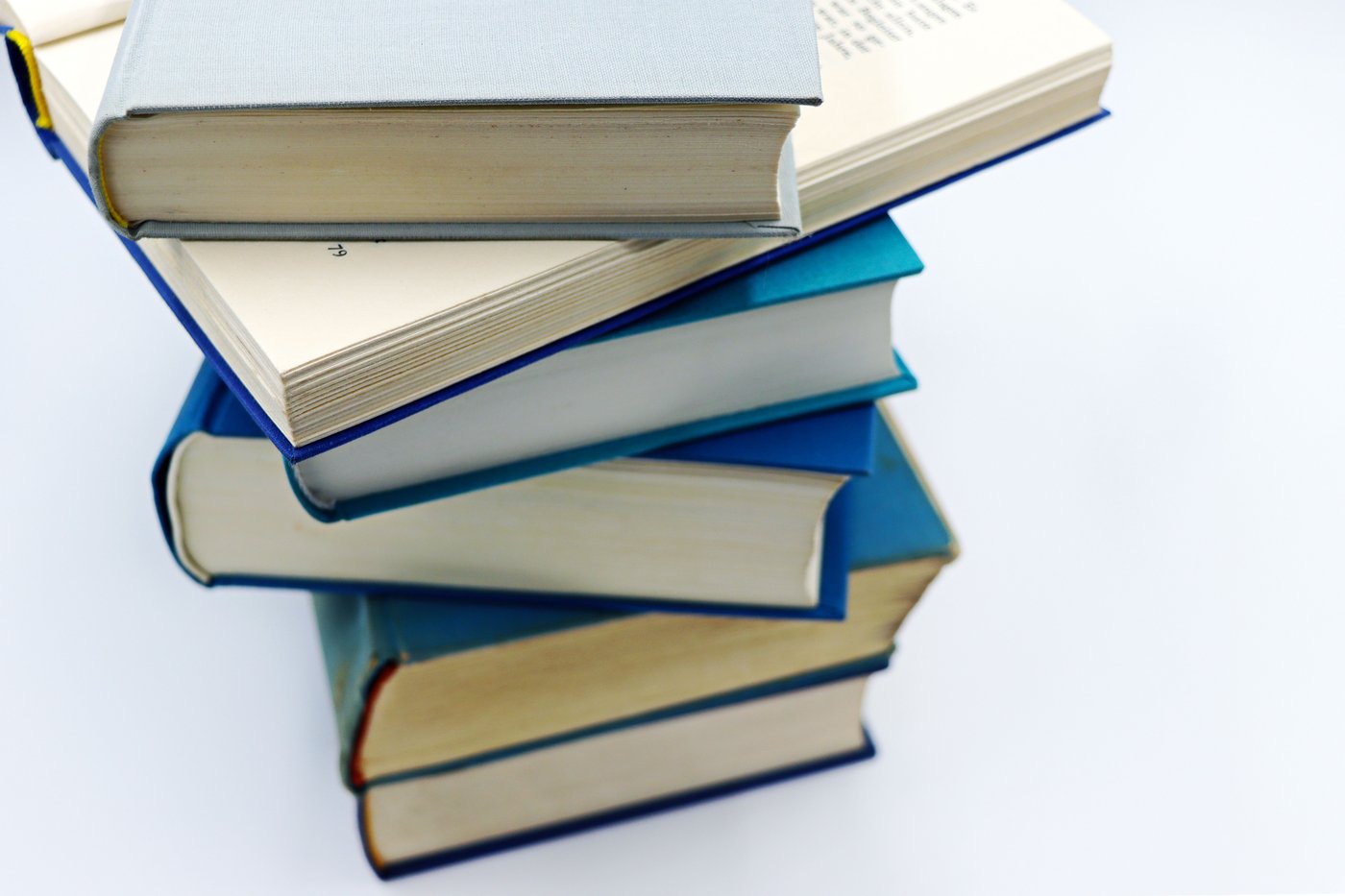 A neat stack of hardcover school books with blue and white cloth spines on a white surface