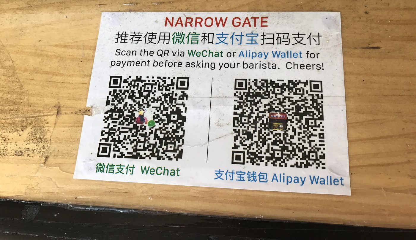 A printed sign on a counter with WeChat Pay and Alipay QR codes