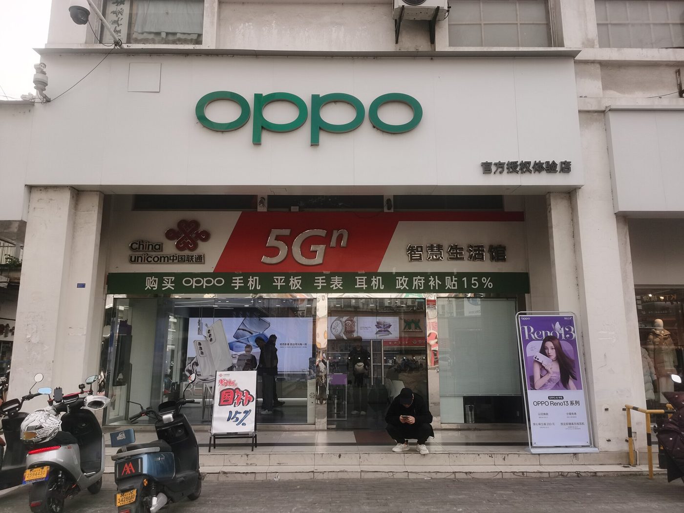 An OPPO smartphone store in Suzhou, China, with a storefront sign advertising a 15% government trade-in discount on new phones.