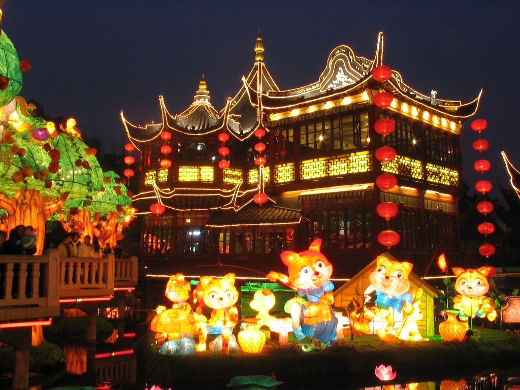 Yuyuan Garden's zigzag bridge and pavilions lit up at night, reflected in the water, Shanghai
