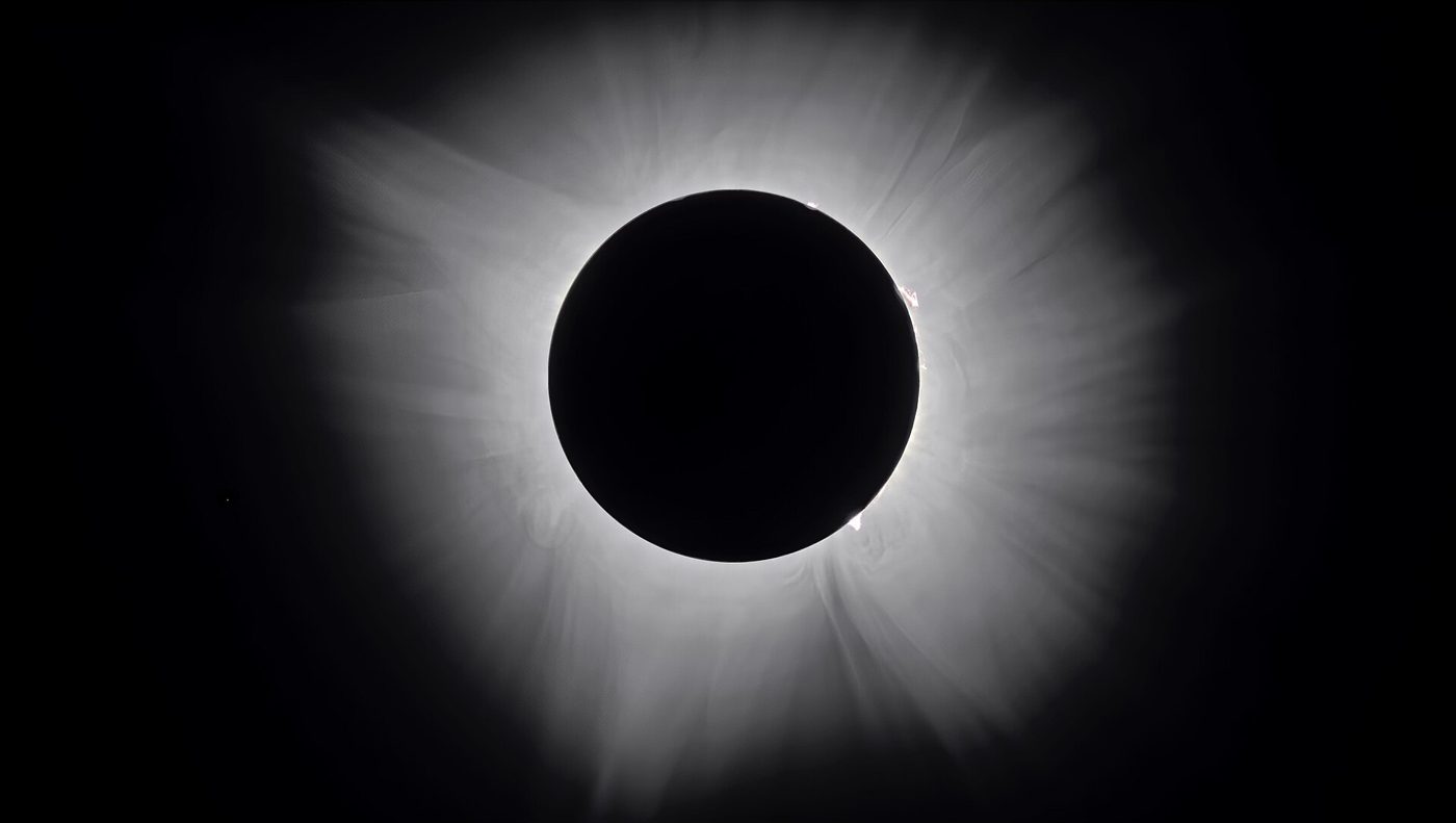 The sun's corona glowing around the dark disc of the moon during totality
