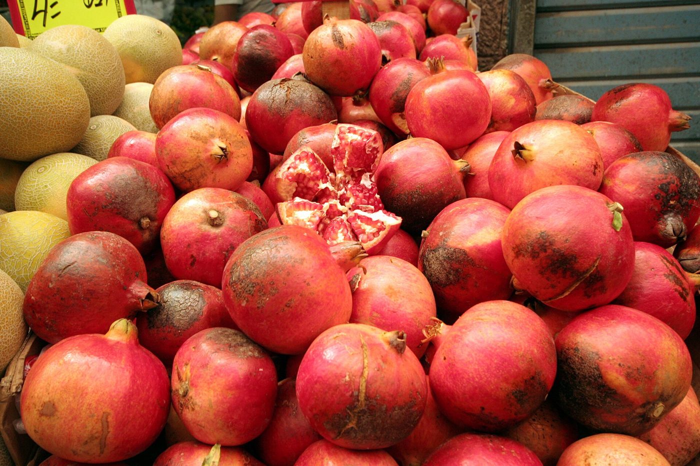 Fresh pomegranates piled up for sale at a fruit market stall.