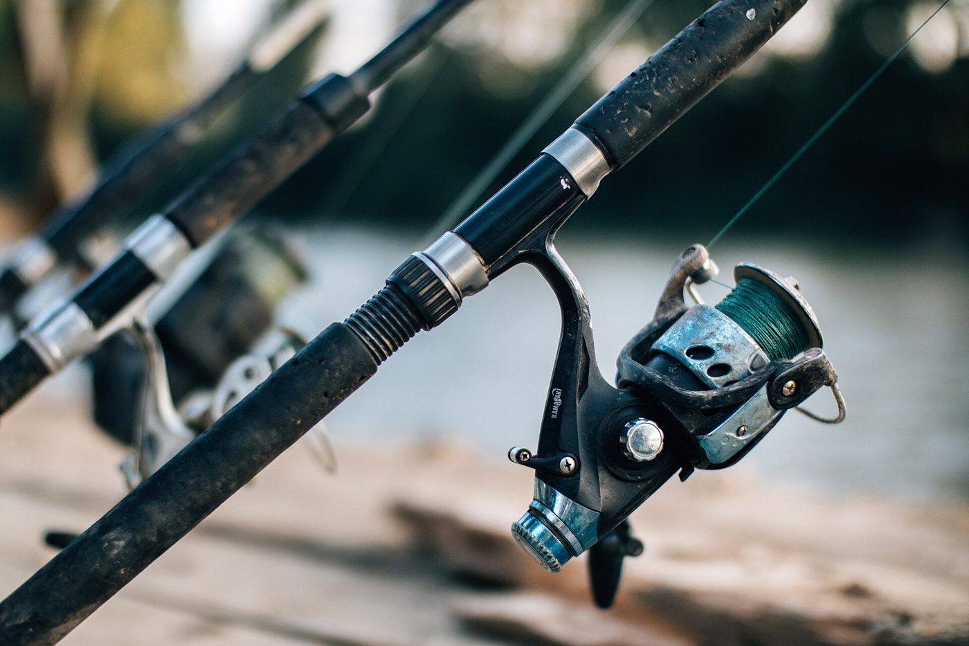 Several fishing rods leaning against a railing along a riverbank