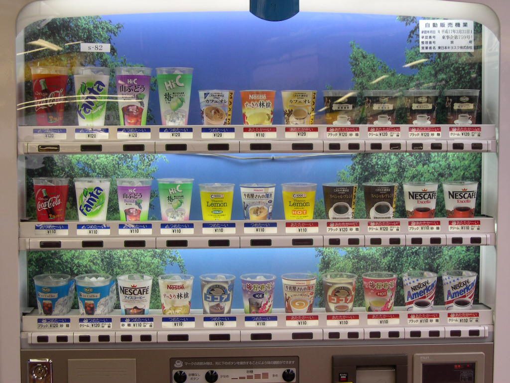 A streetside vending machine with a brightly lit case, rows of canned hot coffee and cold drinks visible inside.